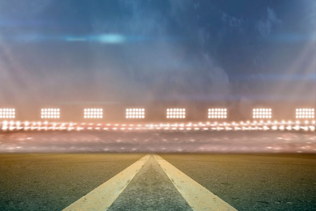 Estádio iluminado à noite com pista vazia, pronto para eventos esportivos e ativações de marca.