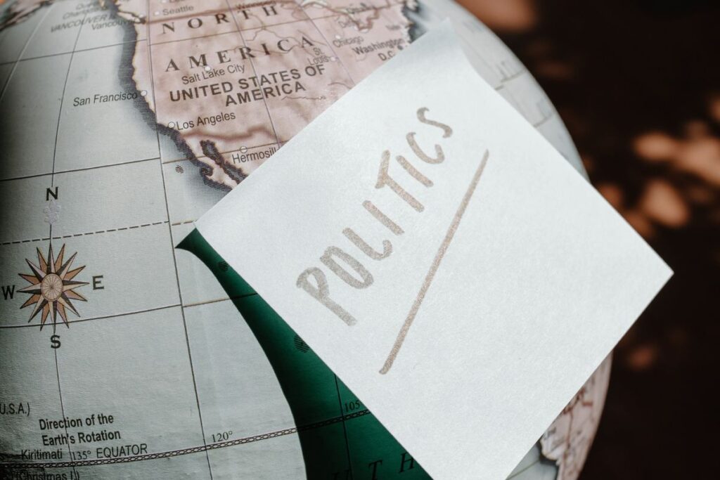 Um post-it branco com a palavra "POLITICS" (política) escrita, colado sobre o mapa dos Estados Unidos em um globo terrestre, representando a abrangência global da política.