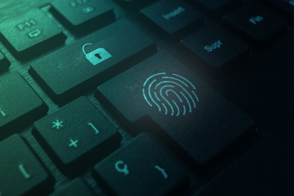 Um teclado escuro com uma tecla de impressão digital iluminada em azul-esverdeado e uma tecla de cadeado aberto, simbolizando segurança biométrica e acesso.