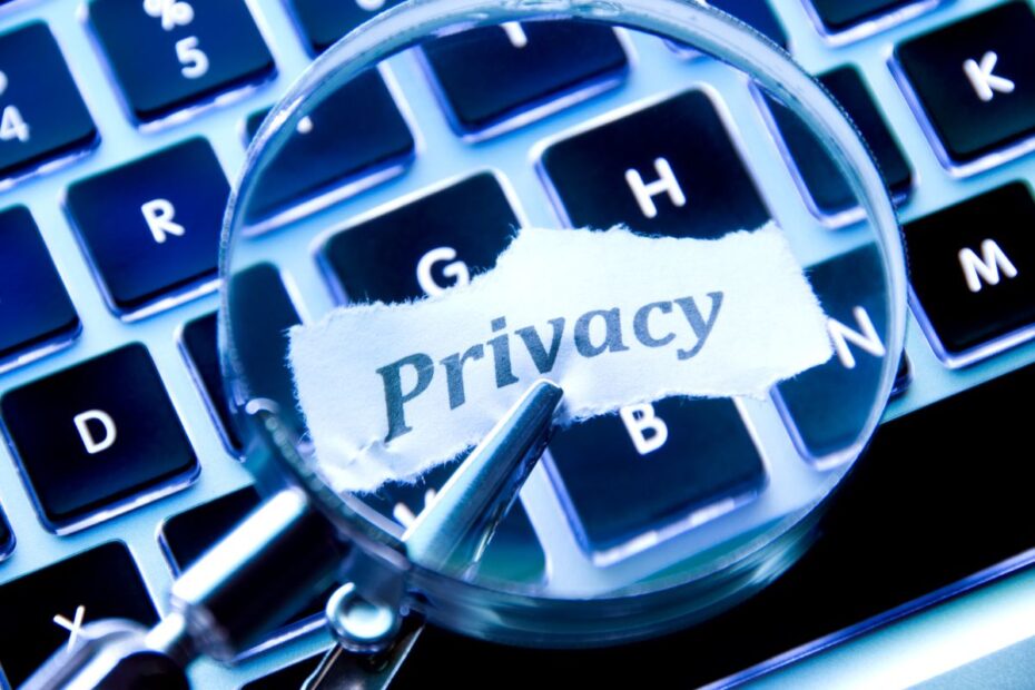 Uma lupa amplificando a palavra "Privacy" escrita em um pedaço de papel sobre um teclado de laptop.